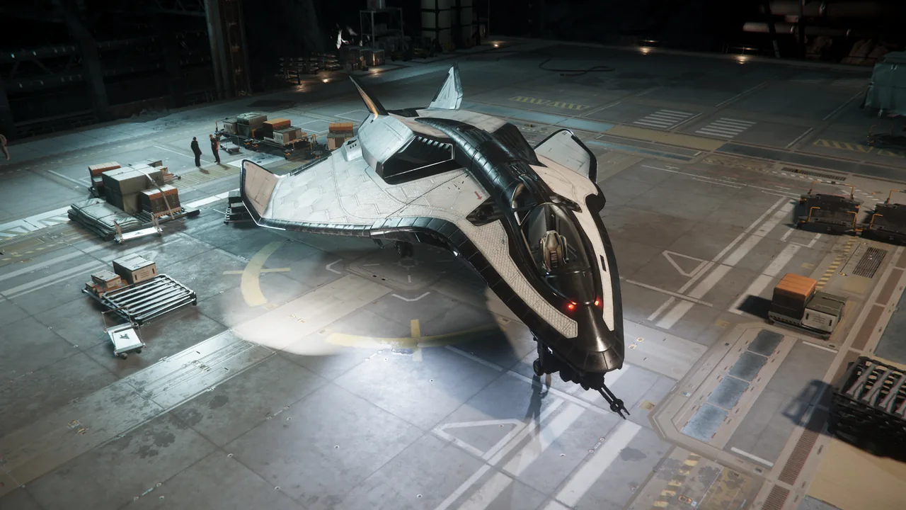 An Avenger Titan, a small freighter with a white and black hull, parked on a hangar floor beside stacked cargo crates